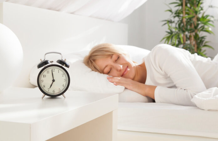 beautiful girl sleeping in her bed. focus on clock